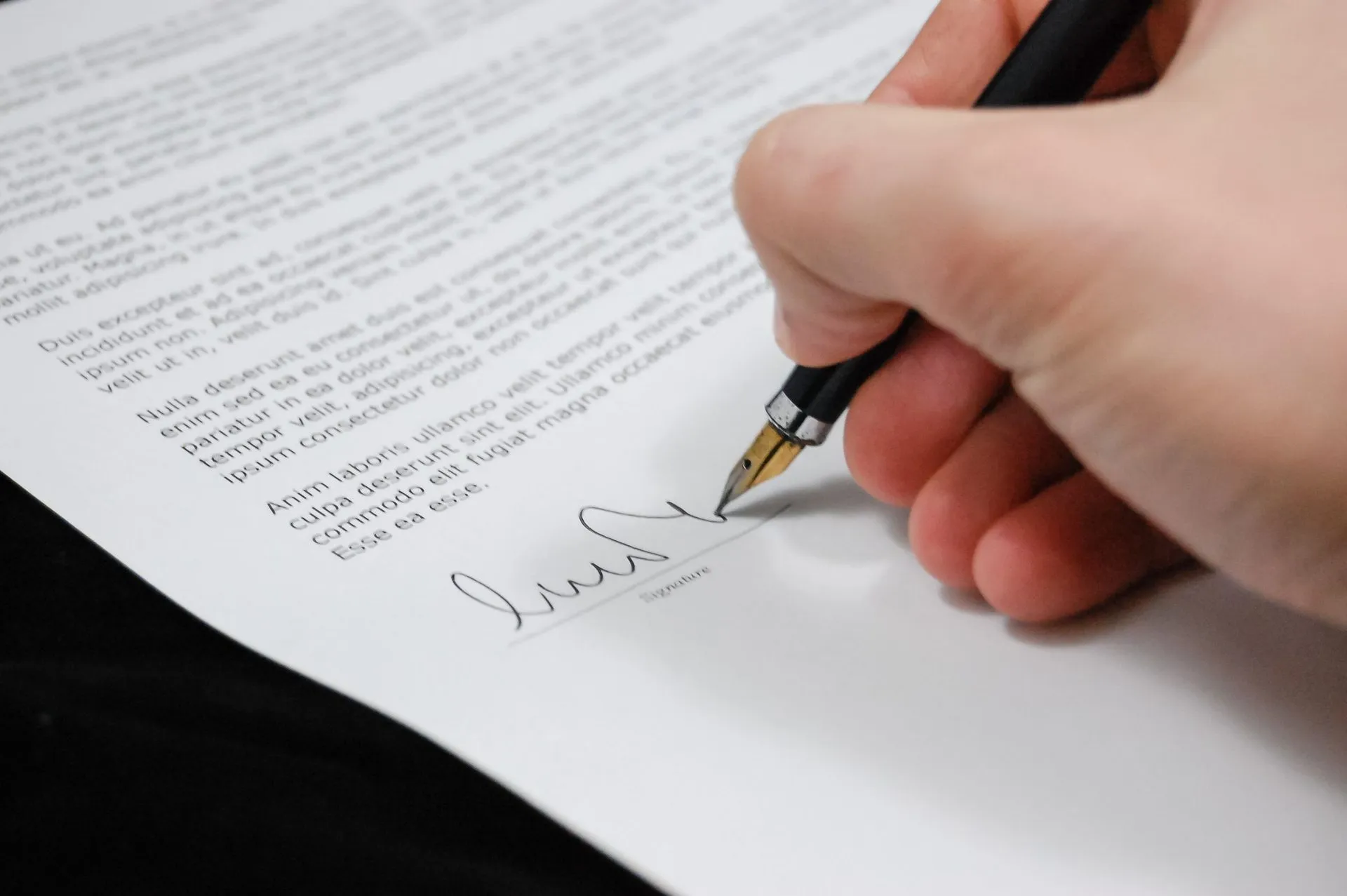 Close-up of a fountain pen signing the signature line of a service agreement